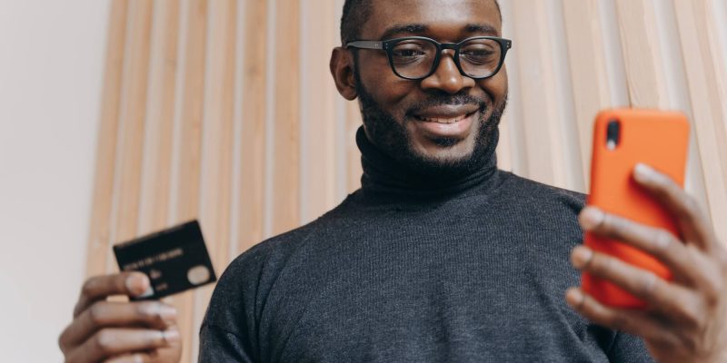 cheerful-african-american-businessman-holding-credit-card-and-smartphone-for-shopping-in-internet-1.jpg